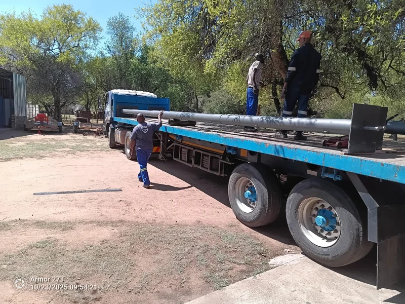 Loading long shafts: The team loading long roller door shafts onto a flatbed by hand, with the end plates already fitted.