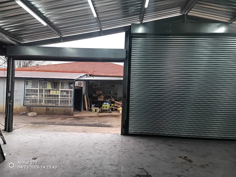 Roll-up door beside a new opening: A roll-up door installed next to a freshly framed steel opening, ready for its own door.